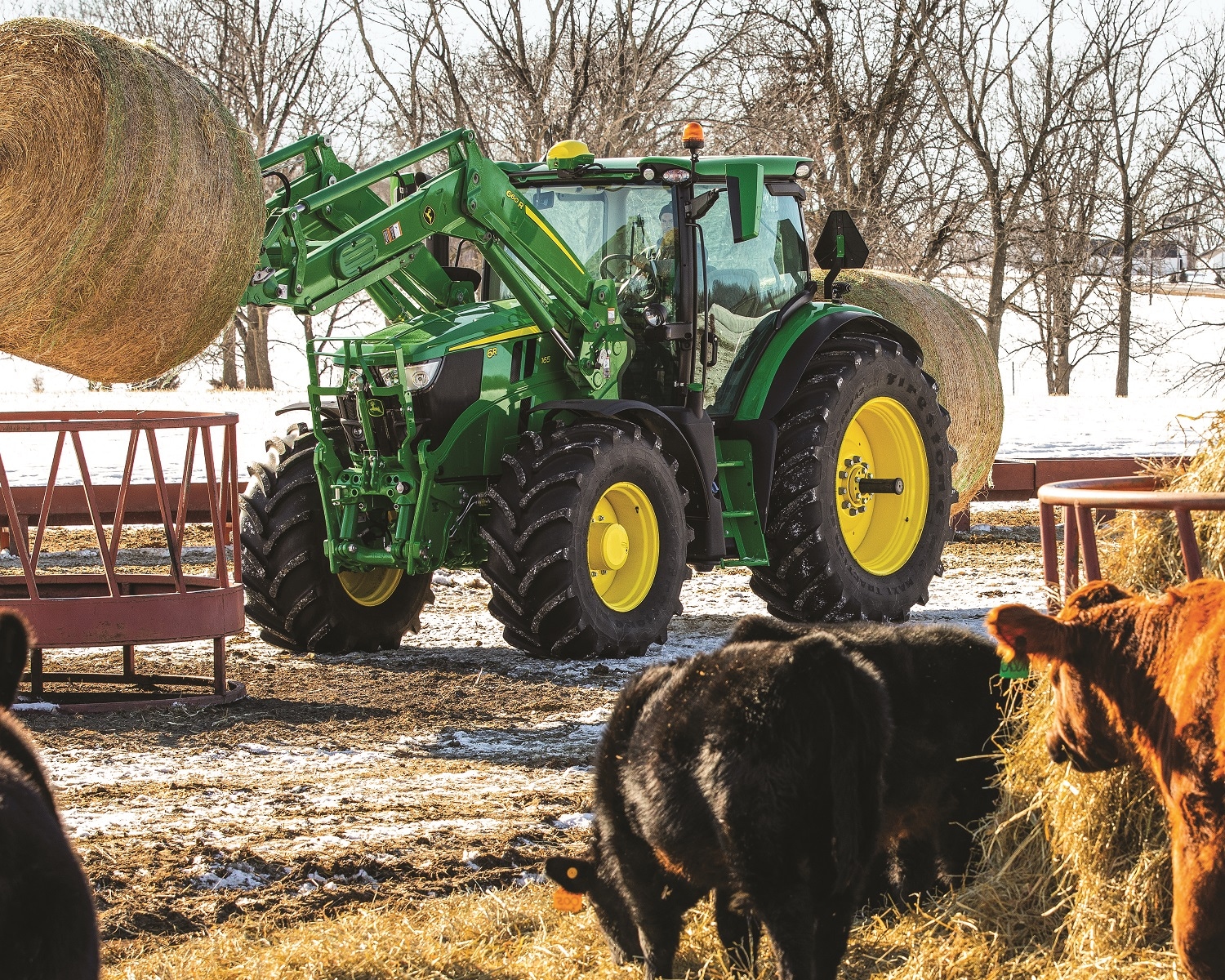 New John Deere loader carrying a hay bale